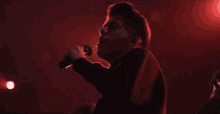 a man is singing into a microphone in front of a red light .