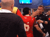 a man in a red jersey with the number 6 on it talks to another man