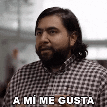 a man with a beard is wearing a plaid shirt and saying a mi me gusta in spanish .