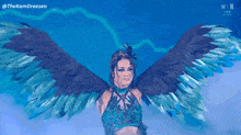 a woman with wings is standing in front of a blue sky with the letters n on the bottom