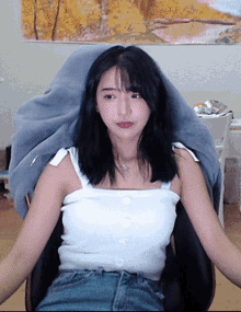 a woman in a white tank top is sitting on a chair