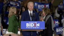 a man stands at a podium with a sign that says biden president on it