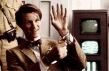 a man in a suit and bow tie is holding up his hand