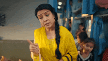a woman in a yellow shirt is pointing at something