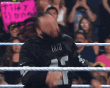 a wrestler wearing a fatu jersey stands in a wrestling ring