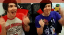 two men are sitting on a couch with their arms in the air