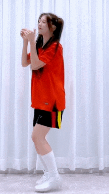 a woman in a red shirt and black shorts is dancing .