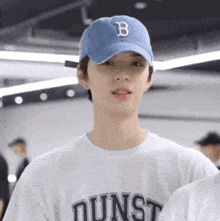 a young man wearing a white shirt and a blue hat with the letter b on it .
