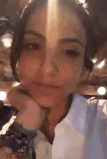 a woman is taking a selfie with her hand on her chin .