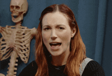 a woman with a skeleton in the background making a funny face