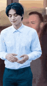 a man in a white shirt and blue pants is standing in front of a man in a suit .
