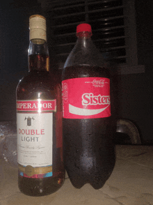 a bottle of emperador double light next to a bottle of coca-cola sisters