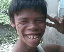 a man making a peace sign with his hand while smiling