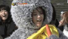a woman is wearing a furry hooded jacket and holding a yellow ribbon ..