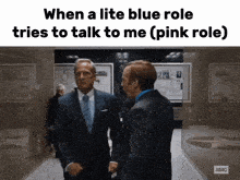 two men in suits are standing in a hallway with the caption " when a lite blue role tries to talk to me ( pink role) "