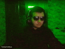 a man wearing headphones is standing in front of a green light .