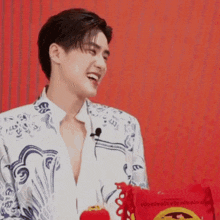 a young man is laughing while holding a red bag in front of a red background .