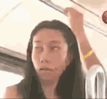 a woman is sitting on a bus with her hand on the ceiling .