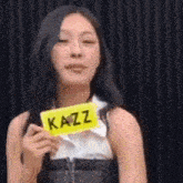a woman is holding a sign that says kazz on it .