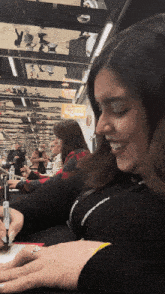 a woman with a ring on her finger is smiling in front of a crowd of people