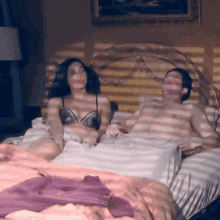 a man and a woman are laying on a bed with a purple blanket