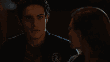 a man and a woman are standing next to each other in a dark room looking at each other .