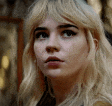 a close up of a woman 's face with blonde hair and earrings