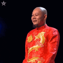 a bald man wearing a red jacket with a dragon on it