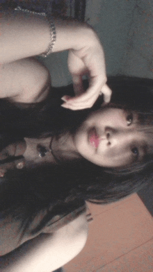 a girl with long black hair is wearing a bracelet