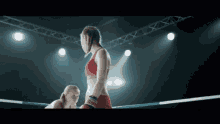 two women are boxing in a ring with one wearing a red top that says ' nfc '