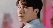 a close up of a man 's face with a pink background and a blue shirt .