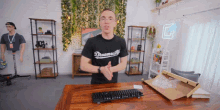 a man wearing a shirt that says dreamuity stands in front of a keyboard