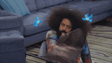 a man with a beard is wrapped in a plaid blanket with two blue birds flying around his head
