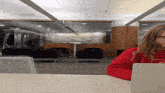 a woman wearing a red sweatshirt that says university is sitting at a desk with a laptop