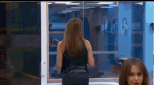 a woman in a black dress is standing in front of a mirror in a gym .