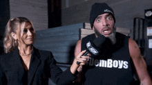 a man wearing a tank top that says den boys is being interviewed