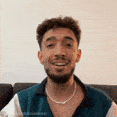 a man with a beard wearing a pearl necklace is smiling