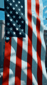 an american flag is waving in the wind with a blue sky in the background