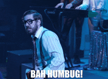 a man in a striped shirt and suspenders says bah humbug on stage