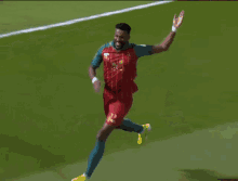 a soccer player wearing a red jersey with arabic writing on it celebrates
