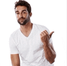 a man with a beard wearing a white t-shirt is pointing to his left