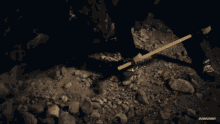 a yellow shovel is laying on a pile of rocks with a subscribe button below it