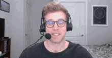 a man wearing glasses and a headset is smiling