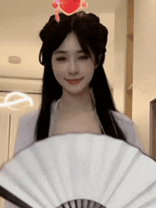 a woman is holding a fan in front of her face