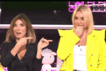 two women are sitting next to each other and one of them is wearing a yellow jacket .