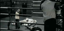 a man is laying on the floor in a boxing ring while a referee looks on