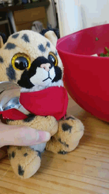 a stuffed animal wearing a red hat is being held by a hand