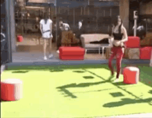 a woman in red pants is walking on a green carpet