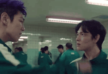 two men are standing next to each other in a hallway .