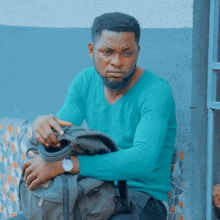 a man in a blue sweater is holding a backpack
